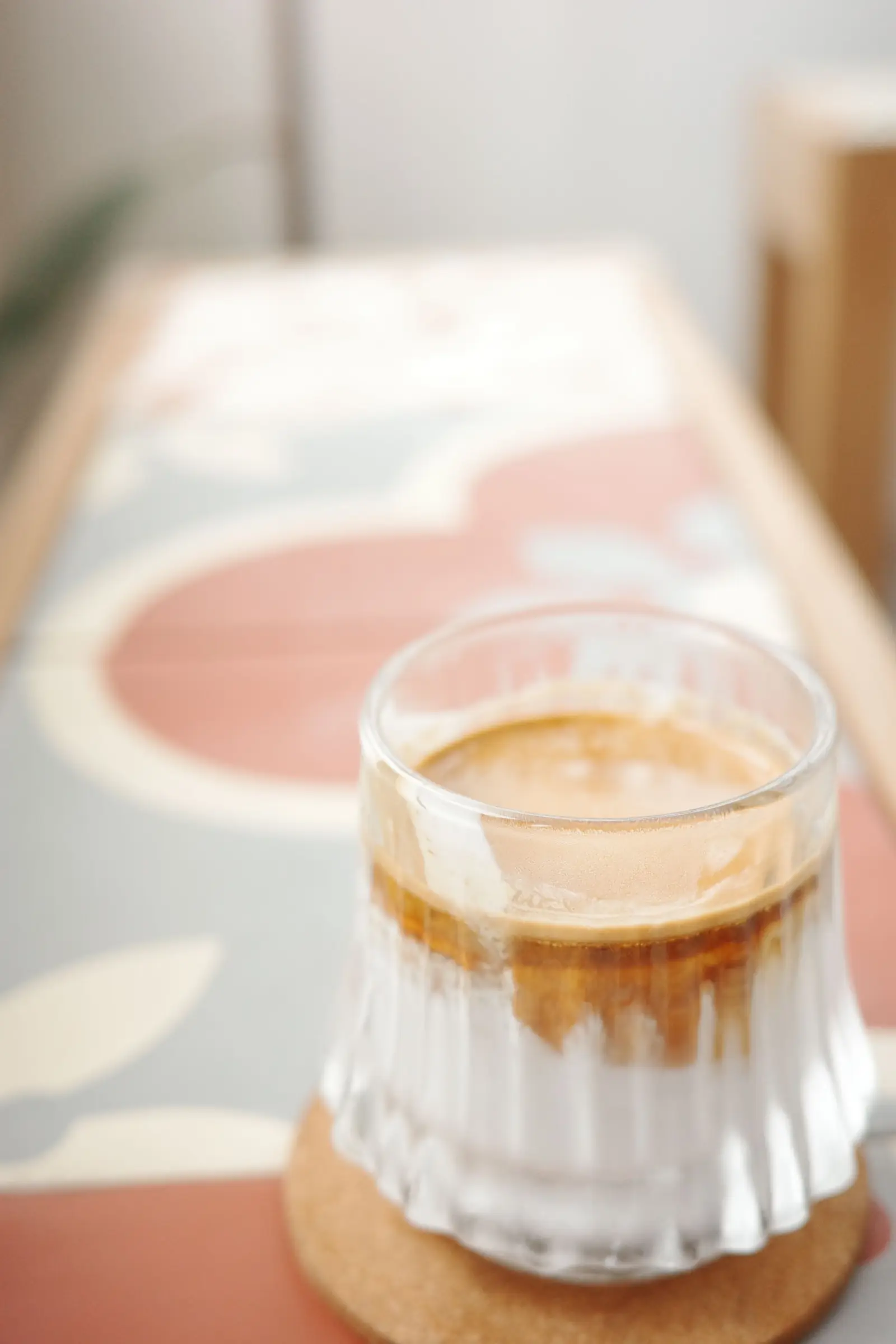 A glass of iced coffee on a patterned table.