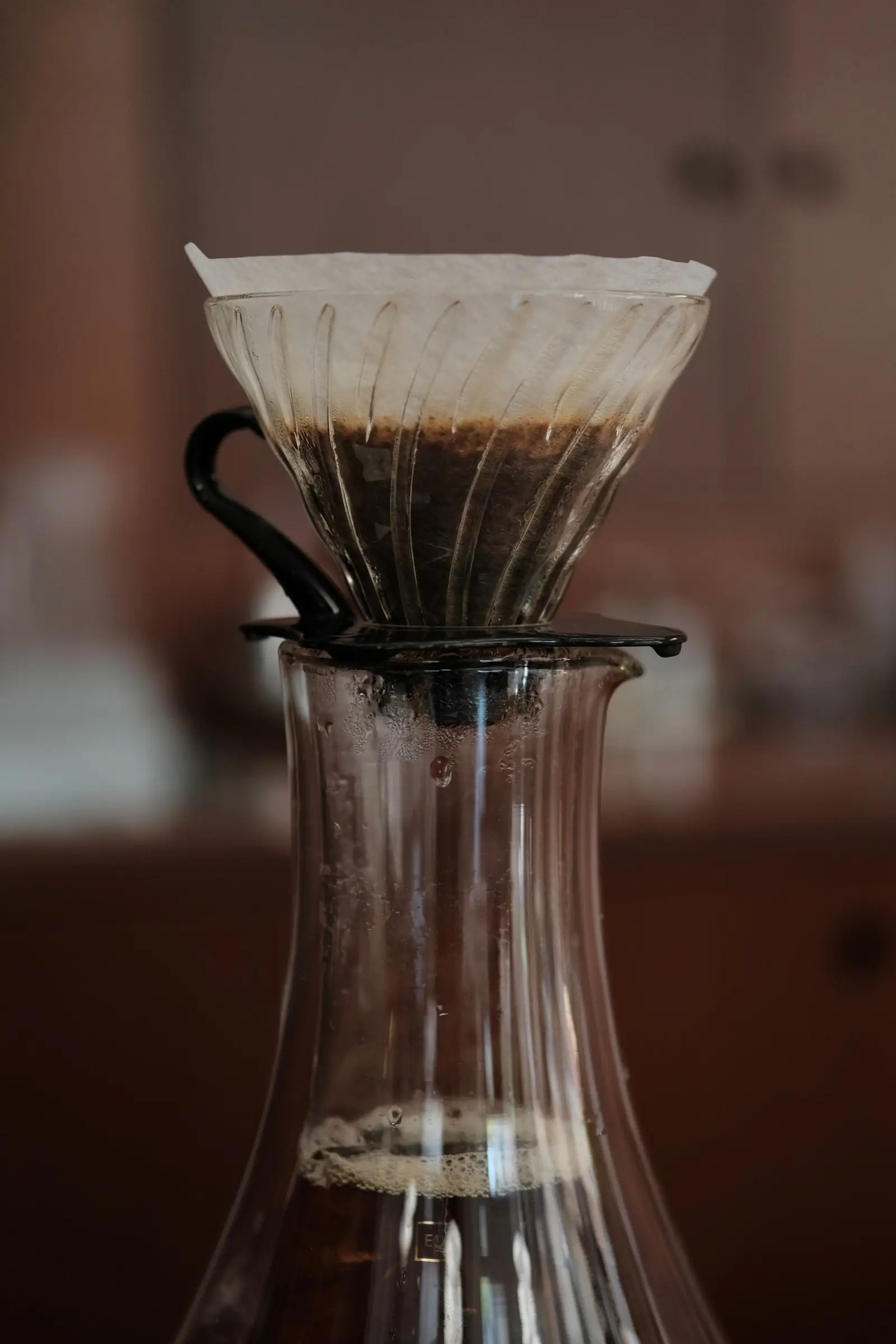 Coffee dripping through a paper filter into a glass carafe.