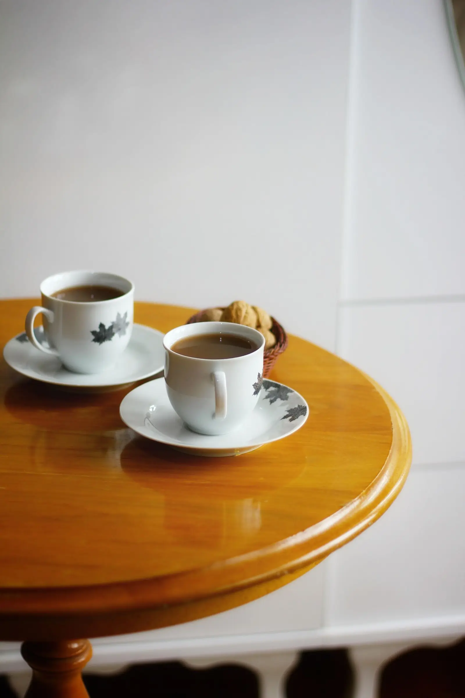 Two cups of coffee side by side on a wooden table.