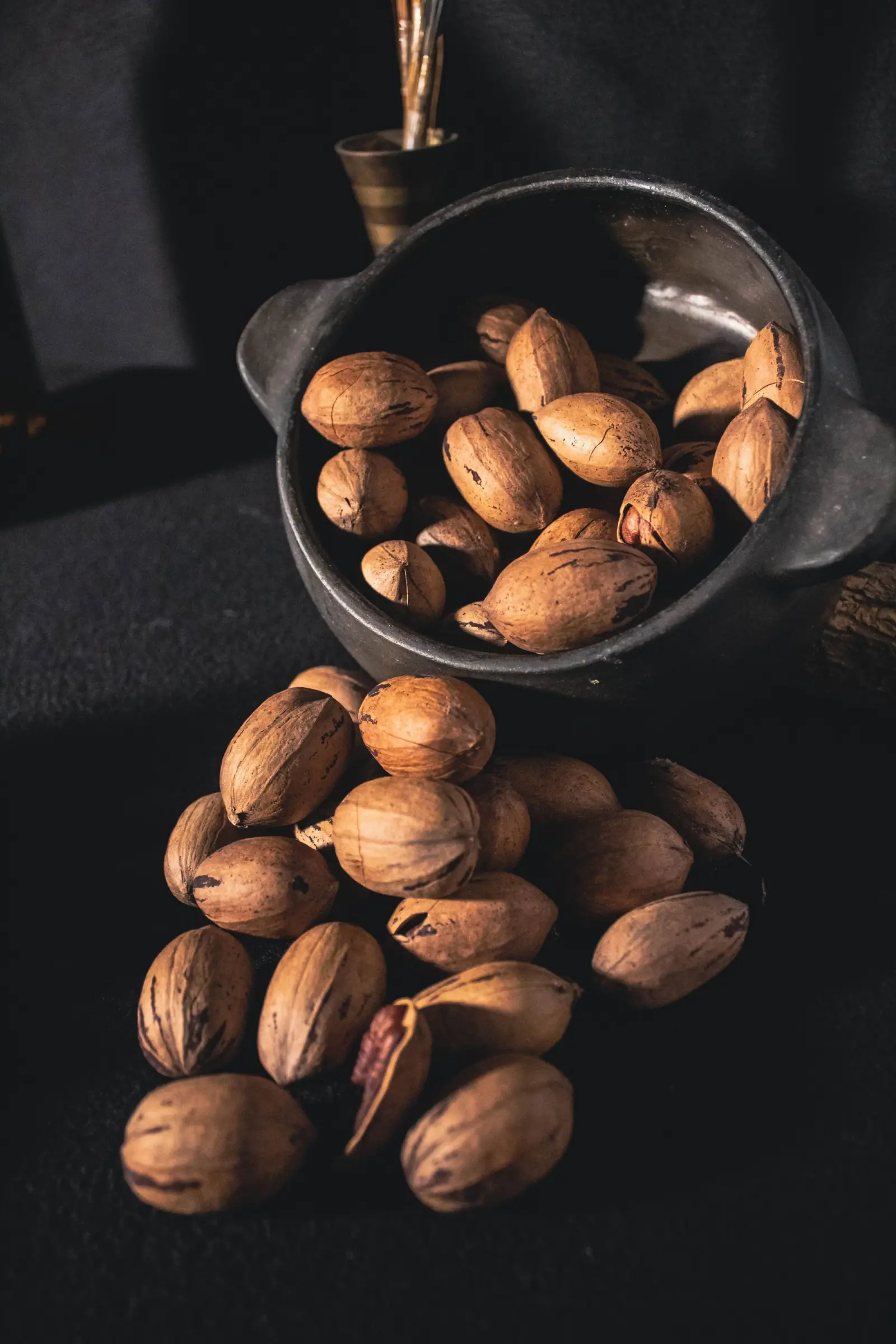 Pecans in their shells in a wooden bowl.